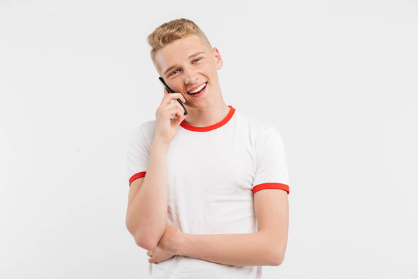 Foto do jovem social vestindo estilo casual falando no smartphone e olhando para você isolado sobre fundo branco
 - Foto, Imagem