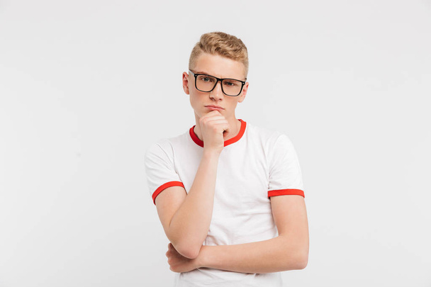 Image of smart serious guy wearing eyeglasses looking at camera with brooding gaze and touching chin, isolated over white background - Fotoğraf, Görsel