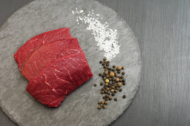 生の肉。ローズマリーとスパイスでまな板の上の牛肉ステーキ. - 写真・画像