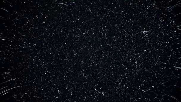weiße Staubpartikel bewegen sich langsam im Raum auf schwarzem Hintergrund. abstrakte Teilchen bewegten Hintergrund. Makrostaubpartikel explodieren in Zeitlupe über schwarzen Hintergrund - Foto, Bild