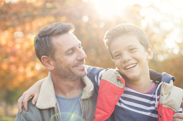 Portrait smiling father and son in front of autumn leaves - Photo, Image