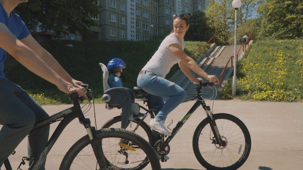 Onnellinen perhe ja pieni poika ajavat polkupyörällä puistossa. Hidastus
 - Materiaali, video