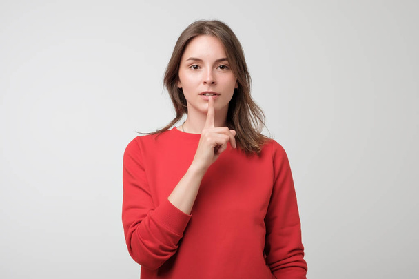 Beautiful european woman in red pulover showing silence sign - Fotoğraf, Görsel