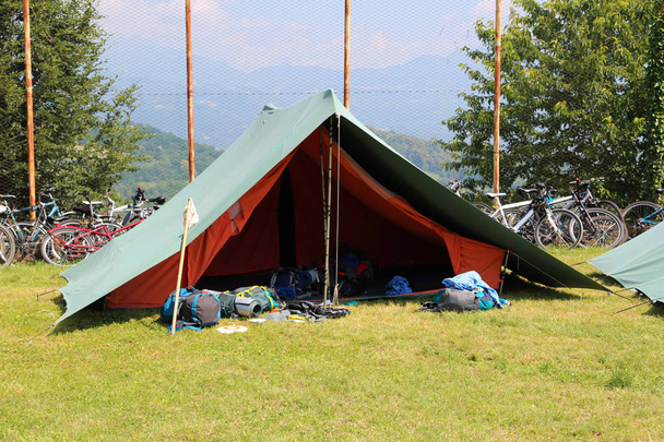 green scout tent with backpacks out and with bikes in the background - Photo, Image
