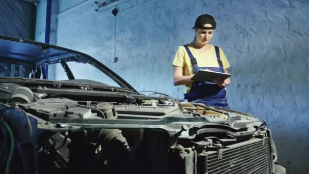 Un meccanico donna utilizza un tablet digitale in un garage di riparazione auto
 - Filmati, video