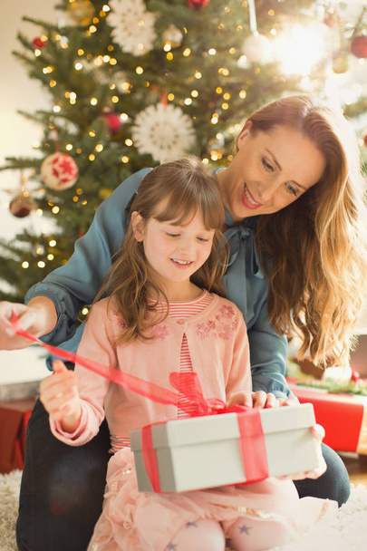 Мать помогает дочери открыть рождественский подарок
 - Фото, изображение
