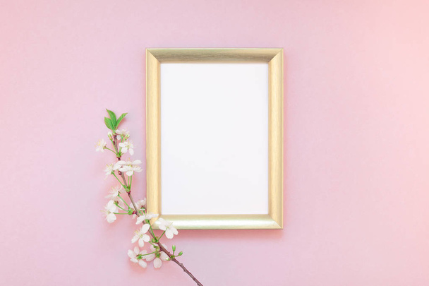 Creativo plano lay concepto vista superior de marco en blanco maqueta y flores de cerezo sobre fondo rosado milenario con espacio de copia en estilo mínimo, plantilla para letras, texto o su diseño
 - Foto, imagen