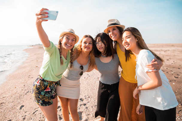 Jovens multirraciais felizes fazendo uma selfie na praia enquanto eles estão em uma festa de verão. Conceito de amigos e férias
 - Foto, Imagem