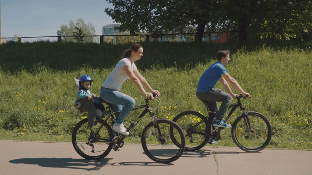Une famille heureuse avec un petit fils fait du vélo dans le parc. Mouvement lent
 - Séquence, vidéo