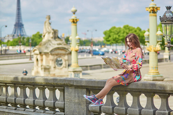 Young beautiful and elegant Parisian woman sitting near the Eiffel tower in Paris - Foto, afbeelding