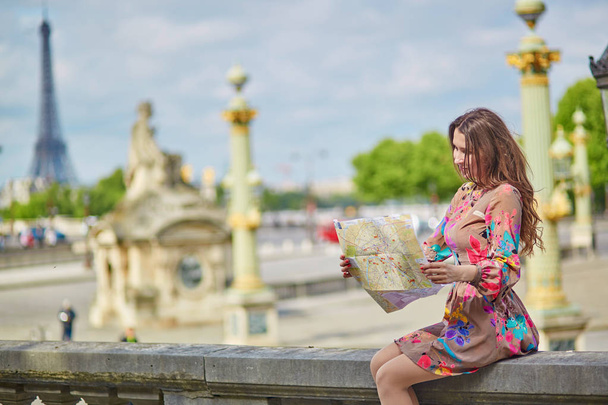 Young beautiful and elegant Parisian woman sitting near the Eiffel tower in Paris - Foto, imagen