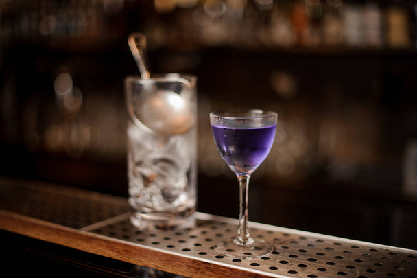 Elegant glass filled with fresh and strong purple colored summer cocktail on the bar counter - Фото, зображення