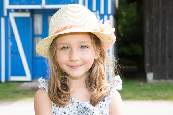feliz cinco años chica jugando al aire libre headshot con paja sombrero flor
 - Foto, imagen