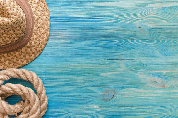 Summer vacation background with copy space. Hat and rope on blue wooden table, top view image. - 写真・画像