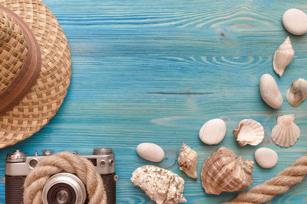 Summer vacation background with copy space. Hat,  photo camera, rope and seashells on blue wooden table background. - Valokuva, kuva
