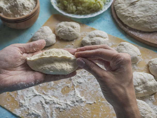 los pasteles caseros de la masa en las manos de las mujeres. El proceso de hacer pasteles con masa de col a mano
. - Foto, imagen