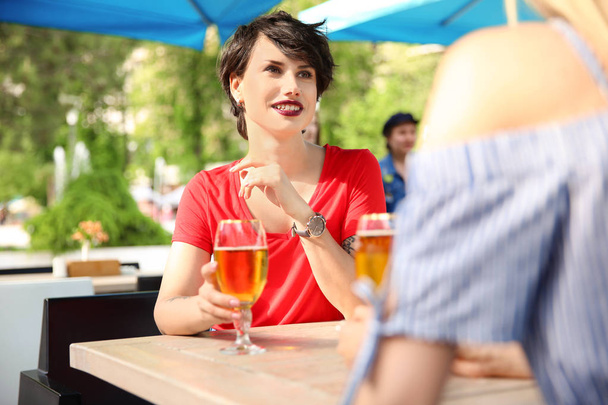 Young women with glasses of cold beer at table - Foto, Imagen