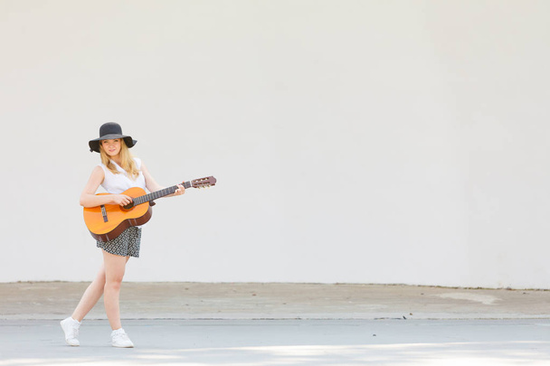 Música, pasión, concepto de hobby. Mujer de pie tocando la guitarra acústica afuera
 - Foto, imagen