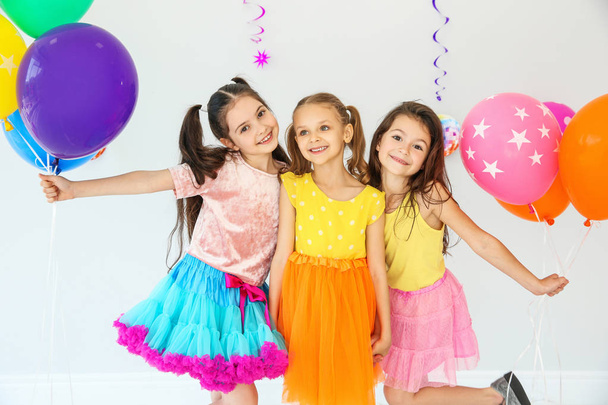 Adorable little girls and decor for birthday party on light background - Foto, Imagem