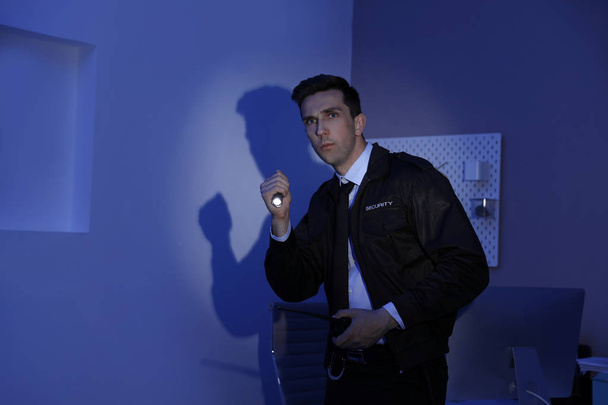Guardia di sicurezza maschile con torcia elettrica e trasmettitore radio portatile in camera oscura
 - Foto, immagini