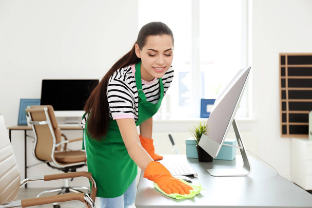 Young woman in apron and gloves cleaning office - Foto, immagini