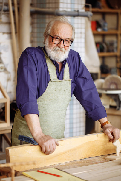 old man in glasses and casual clothes likes to work with wood - Photo, Image
