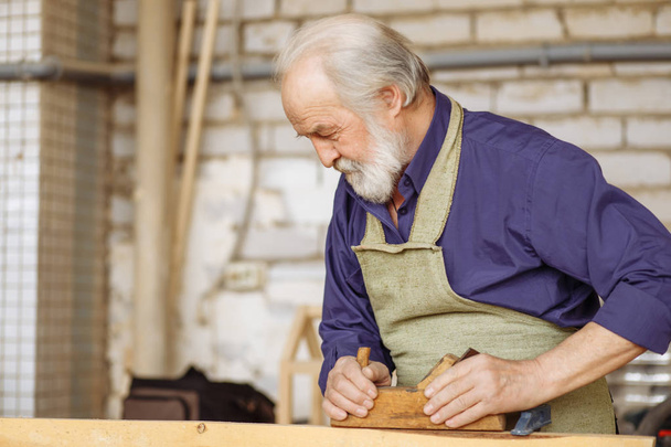 close up side view shot strong pensioner shaping wood - Foto, Bild