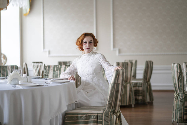 una mujer gravemente enferma moribunda en un vestido blanco esperando el desayuno en un restaurante vacío solo
 - Foto, Imagen