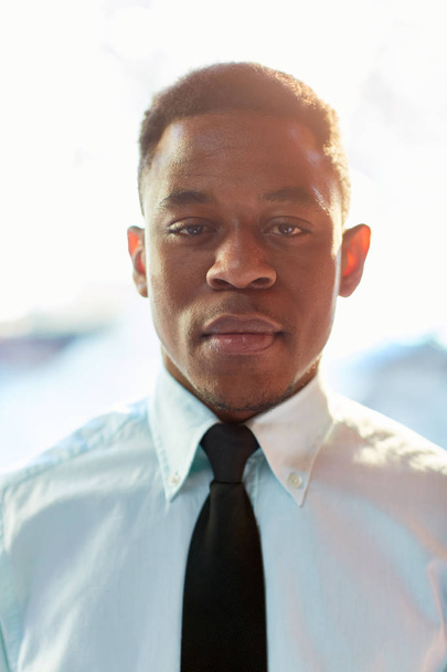 Joven empresario serio de etnia afroamericana con corbata y camisa blanca mirando a la cámara
 - Foto, imagen
