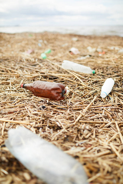 Río tierra de la orilla con hierba seca y un montón de viejas botellas de plástico que necesita ser recogido
 - Foto, Imagen