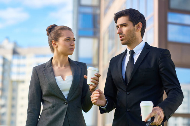Jonge vertrouwen agent in pak leggen zijn collega hoe wij volgende stap in hun bedrijf tijdens buiten koffie-break - Foto, afbeelding
