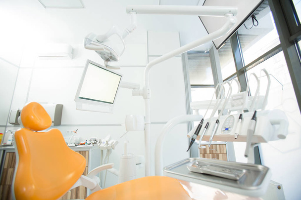 Instrumentos estéreis para check-up dentário em bandeja metálica, conjunto de brocas elétricas, display, lâmpada e poltrona no escritório do dentista
 - Foto, Imagem
