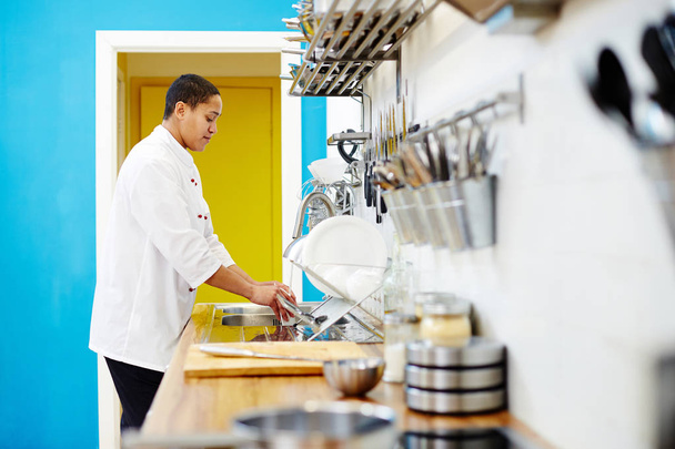 Chef de restaurante lavando platos en fregadero después de cocinar o al final de la jornada laboral
 - Foto, Imagen