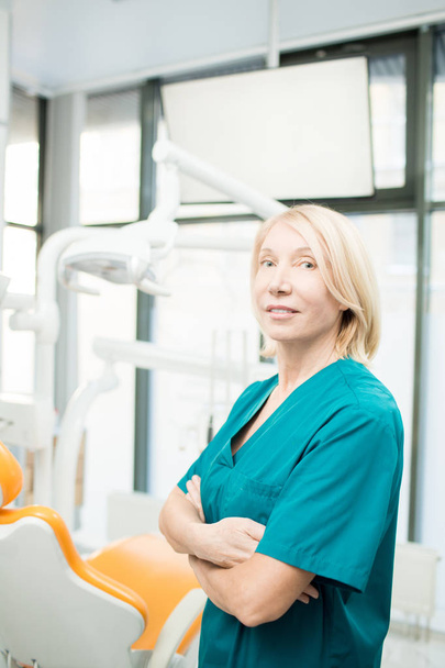 Kobieta dentysty lub asystenta w mundurze, broni jej przekraczania na klatce piersiowej, patrząc na kamery - Zdjęcie, obraz
