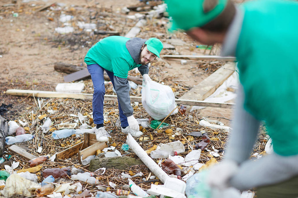 Mitarbeiter einer Umweltschutzfirma holt nicht recycelbaren Müll aus dem Boden - Foto, Bild
