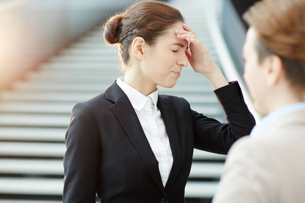 Anxious businesswoman touching her head while colleague reminded her about some working plans - Фото, изображение