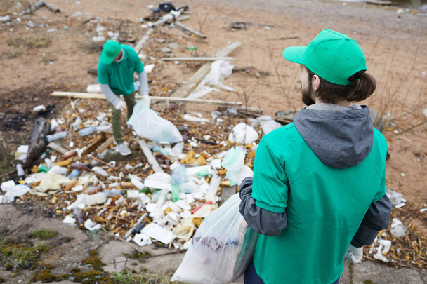 Un pequeño grupo de chicos de Greenpeace recogiendo basura del suelo en territorio abandonado
 - Foto, imagen