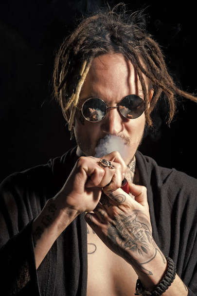 fashion portrait of a man. Hippy smoker with dreadlocks in sunglasses and bare chest - Fotó, kép