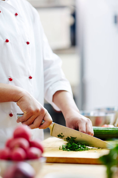 Szef kuchni w mundurze rozdrabniania zielony zioła aromatyczne zupy, gulasz lub sałatka z ostry nóż - Zdjęcie, obraz