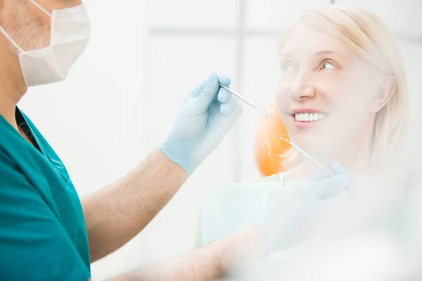 Усміхнений пацієнт дивиться на свого стоматолога в рукавичках і форму перед оглядом зубів
 - Фото, зображення