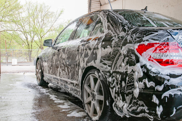 Car washing. Cleaning modern car covered by foam. - 写真・画像