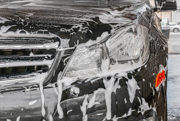 Car washing. Cleaning modern car covered by foam. - Foto, imagen