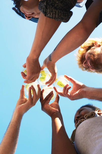 Hands of five friends holding glasses with lemonade and clinking them against blue sky - Photo, image