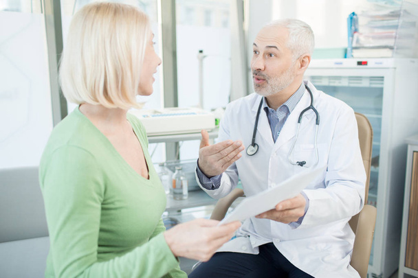 Doktor vysvětlovat jeho pacienta podrobnosti o lékařský předpis během schůzky v klinikách - Fotografie, Obrázek