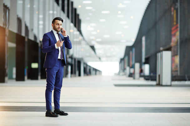 Młody agent elegancka w kolorze consulting jego klienta podczas zagranicznych podróży stojąc w nowoczesne Lotnisko - Zdjęcie, obraz
