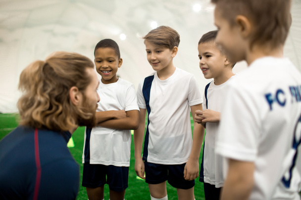 Treinador de esportes consultando sua equipe de futebol de quatro meninos antes do novo jogo ou competição
 - Foto, Imagem