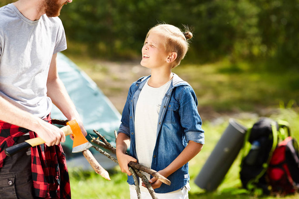 Kleiner Pfadfinder mit Stöcken im Gespräch mit seinem Vater während ihrer Reise am Sommerwochenende - Foto, Bild