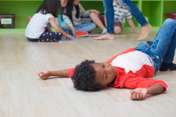 Afro-Amerikaanse jongen met eenzaamheid emoties onderscheiden groep vrienden in klas kleuterschool preschool.bullying depressie concept - Foto, afbeelding