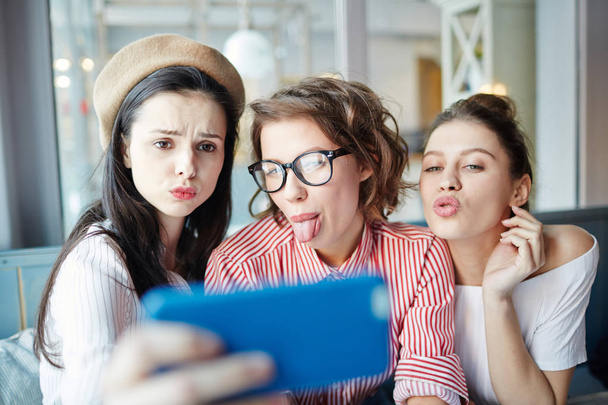 Şirin kızlar sınıflar arasındaki mola sırasında Smartphone'da fotoğraf çekimi sırasında komik surat - Fotoğraf, Görsel