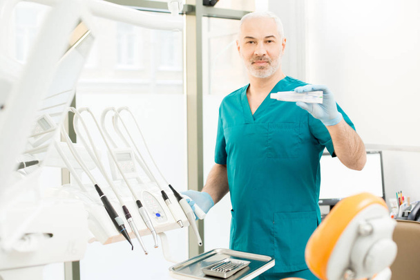 Досвідчений стоматолог показує нову ефективну зубну пасту для зміцнення і відбілювання зубів
 - Фото, зображення